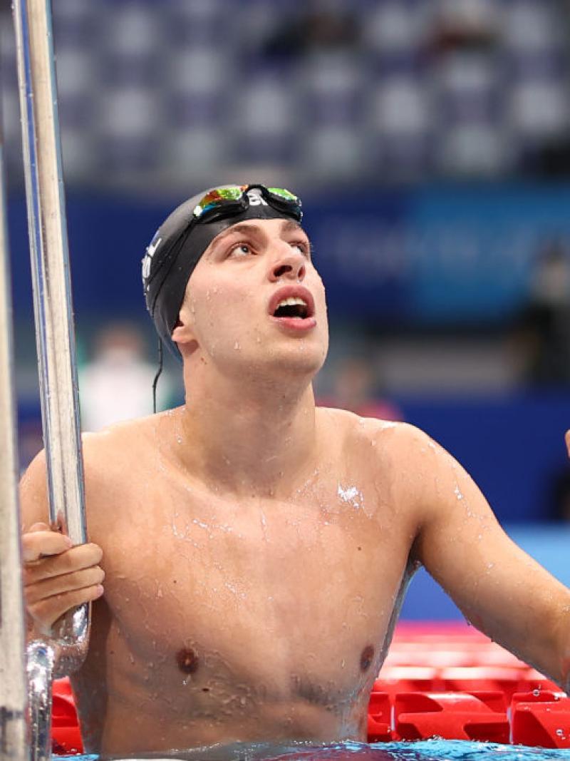 A male Para swimmer is using the handrails to leave the pool after a competition