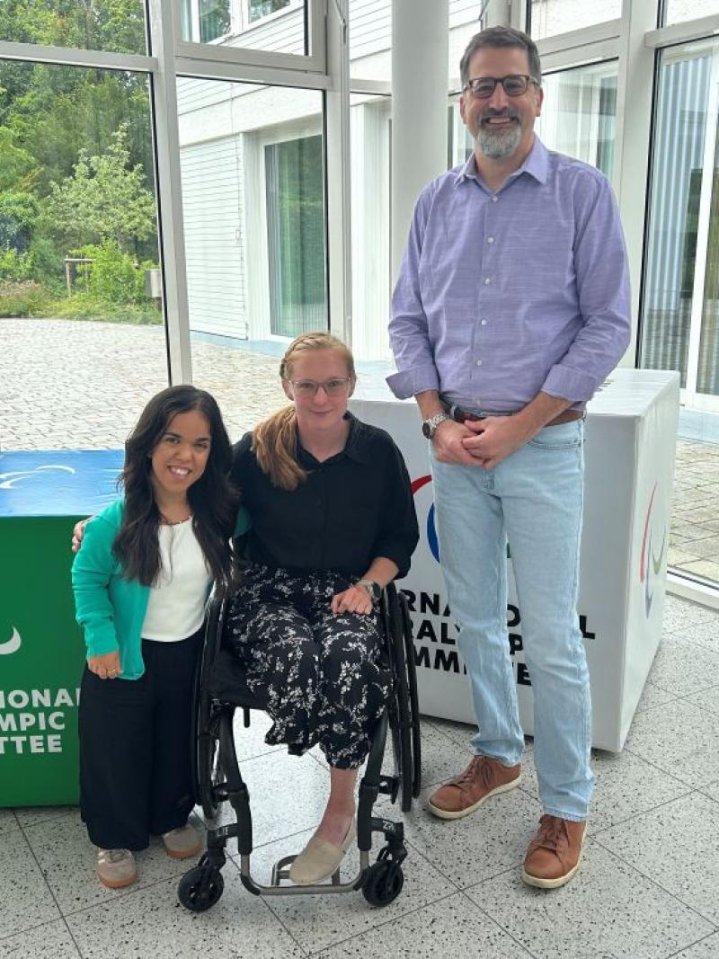 Two female Para athletes and IPC CEO Mike Peters pose for a photo at the IPC headquarters