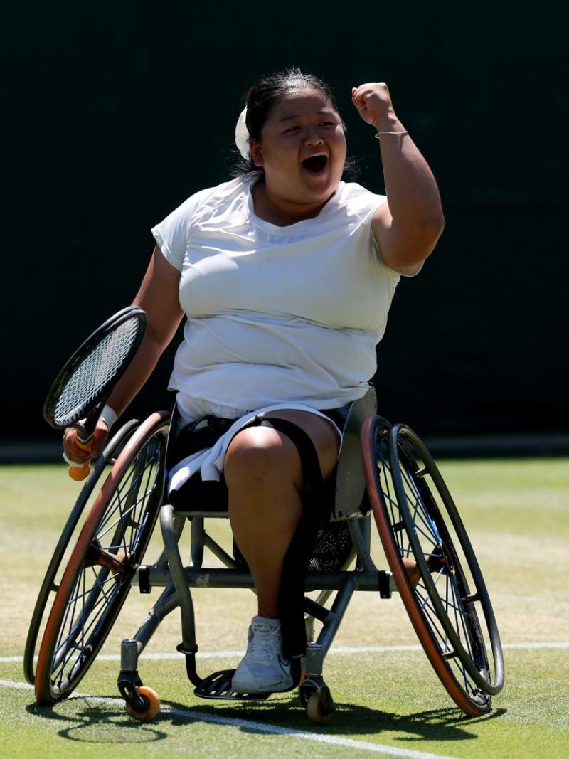 A female wheelchair tennis player is pumping her fist