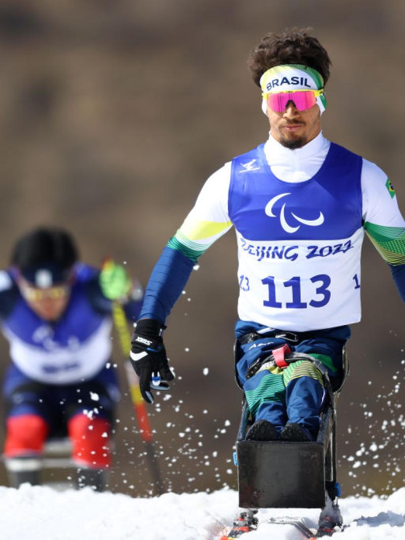 A male Para athlete competing in Para cross-country skiing on a sit-ski