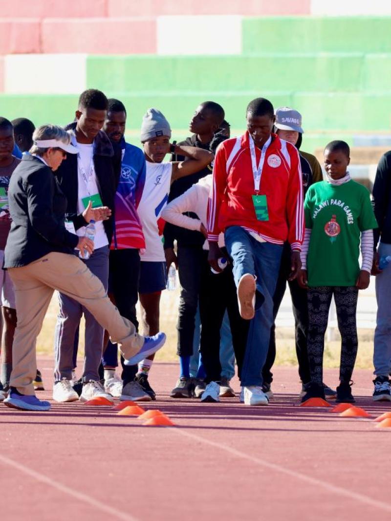 About 25 athletes gather on a track during a training camp