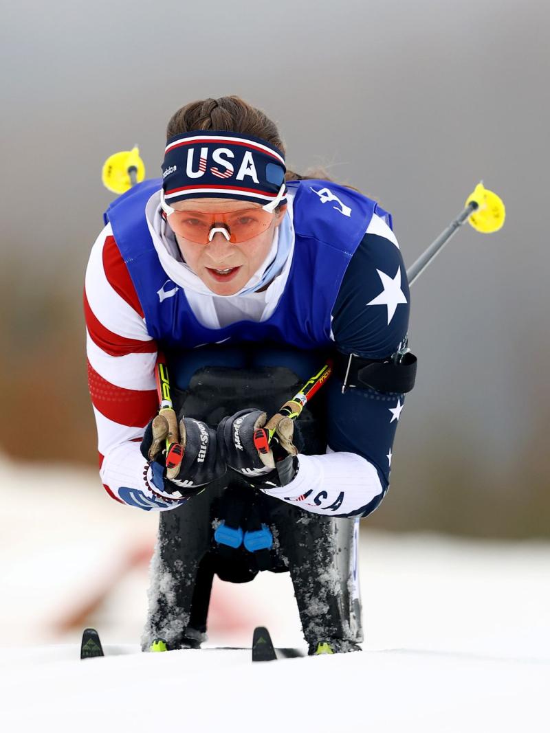 A female sit-skier is competing in a cross-country race