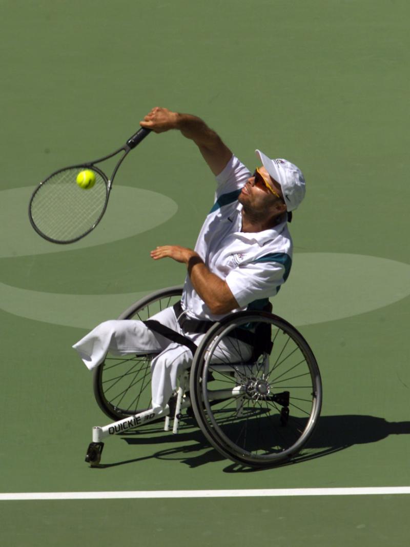 A male wheelchair tennis player is in competition on a grass court