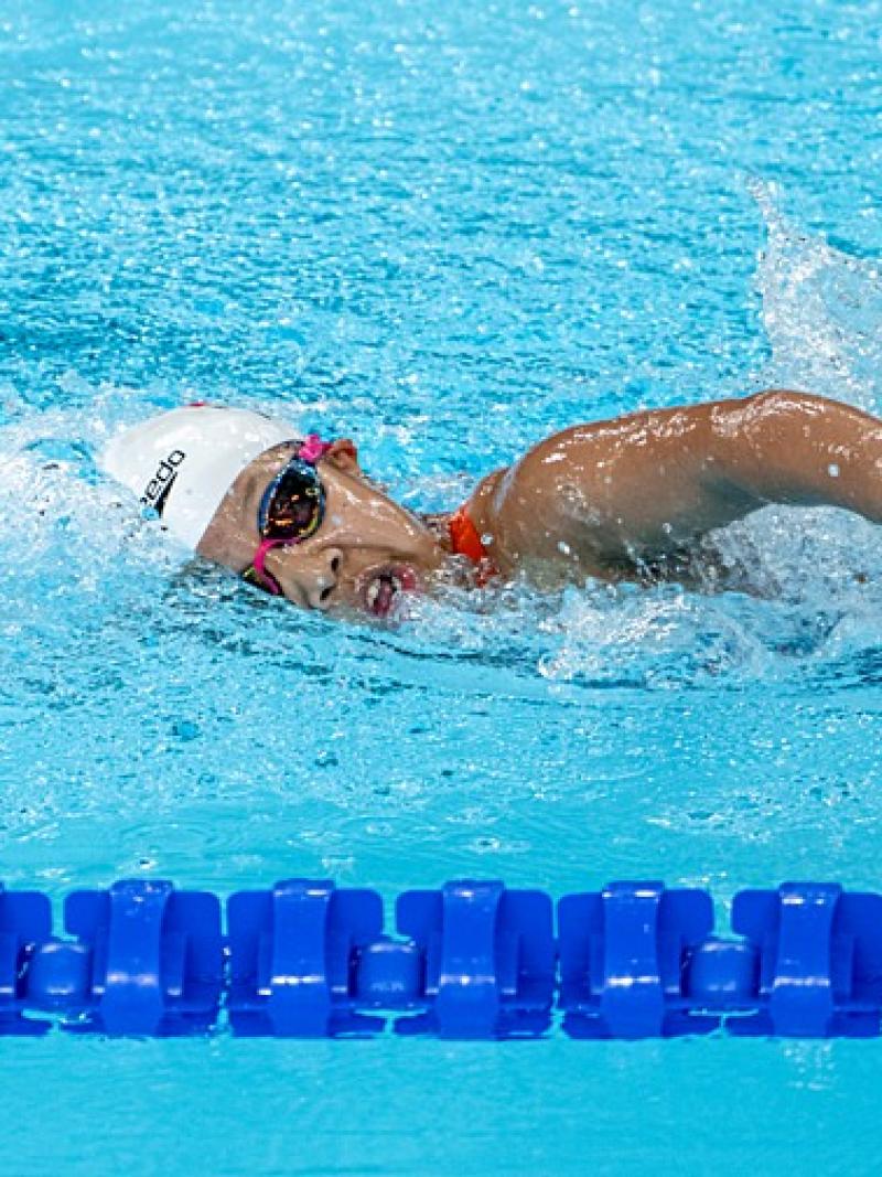 A female Para swimming athlete is competing in a freestyle event
