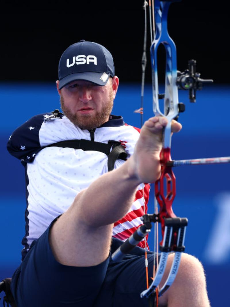 A Para archery athlete aims the bow using his right feet
