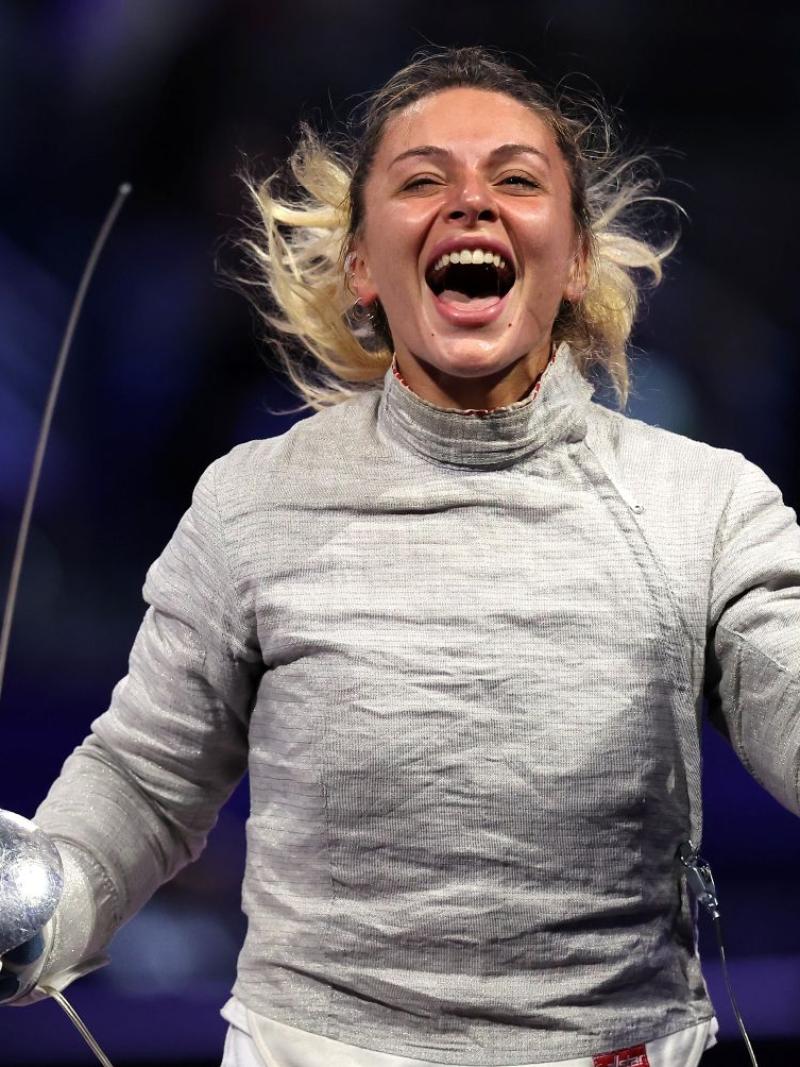 A female athlete smiling and pumping her fist following a wheelchair fencing competition
