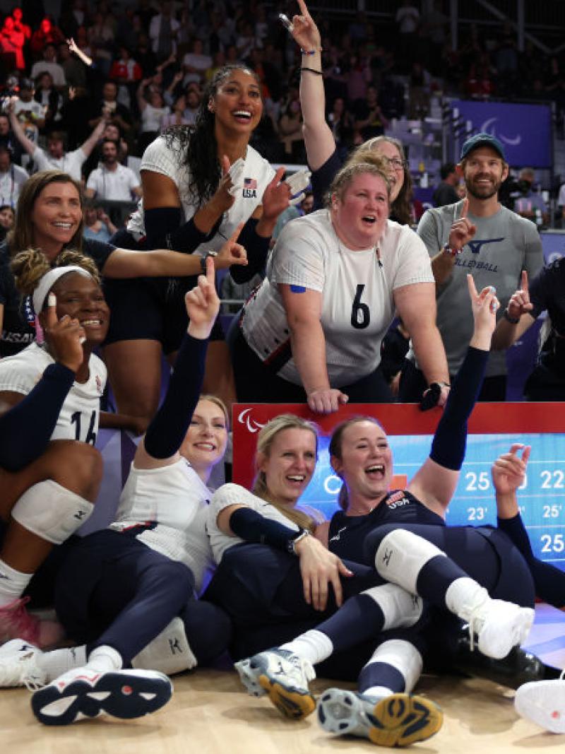 Female sitting volleyball players are celebrating in front of a scoreboard at the Paris 2024 Paralympic Games