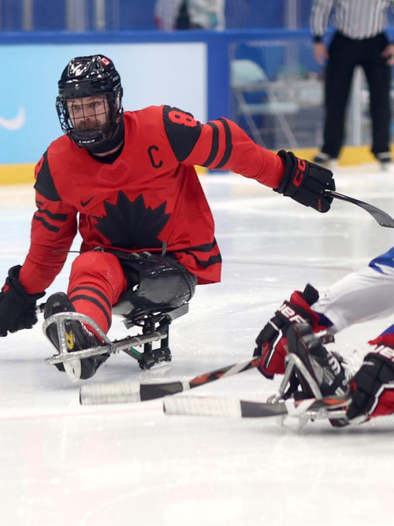 A male Para ice hockey player is scoring a goal