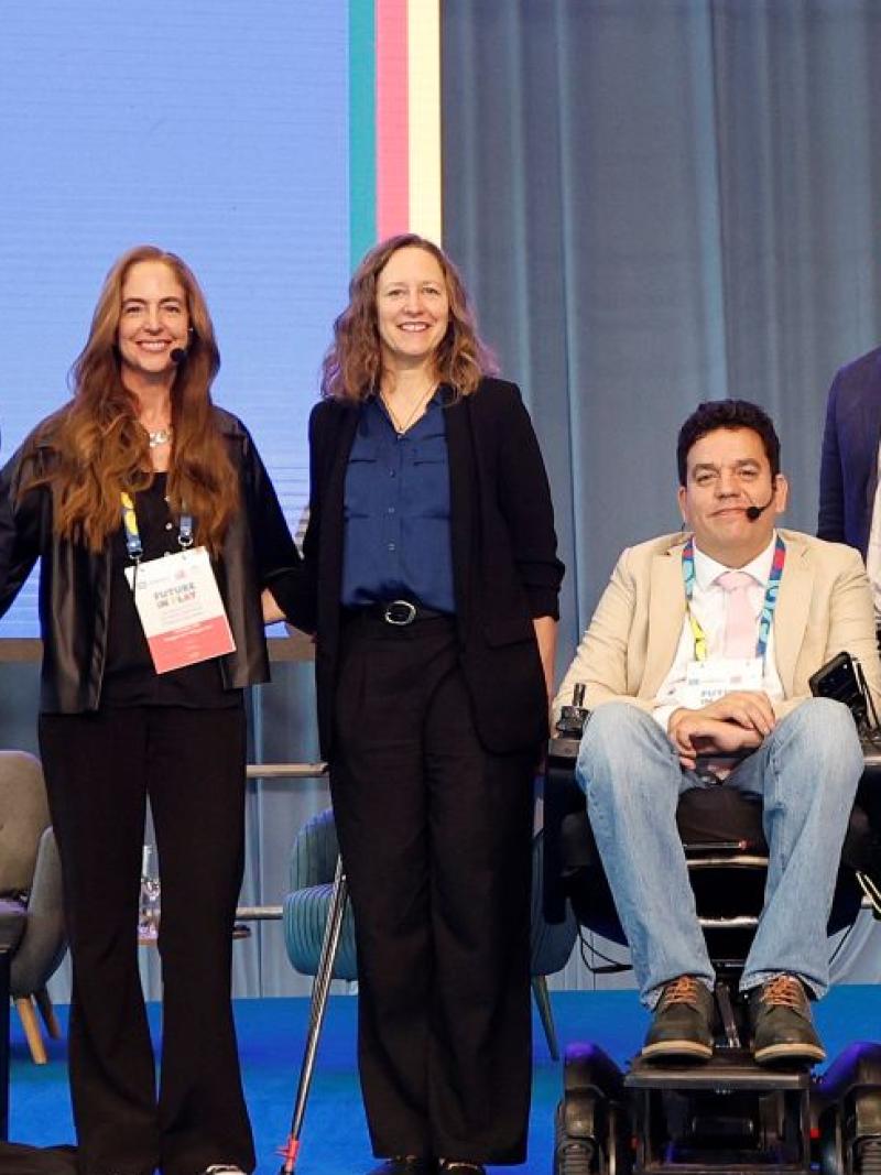 Six people pose for a group photo in front of a screen that says "Future in Play"