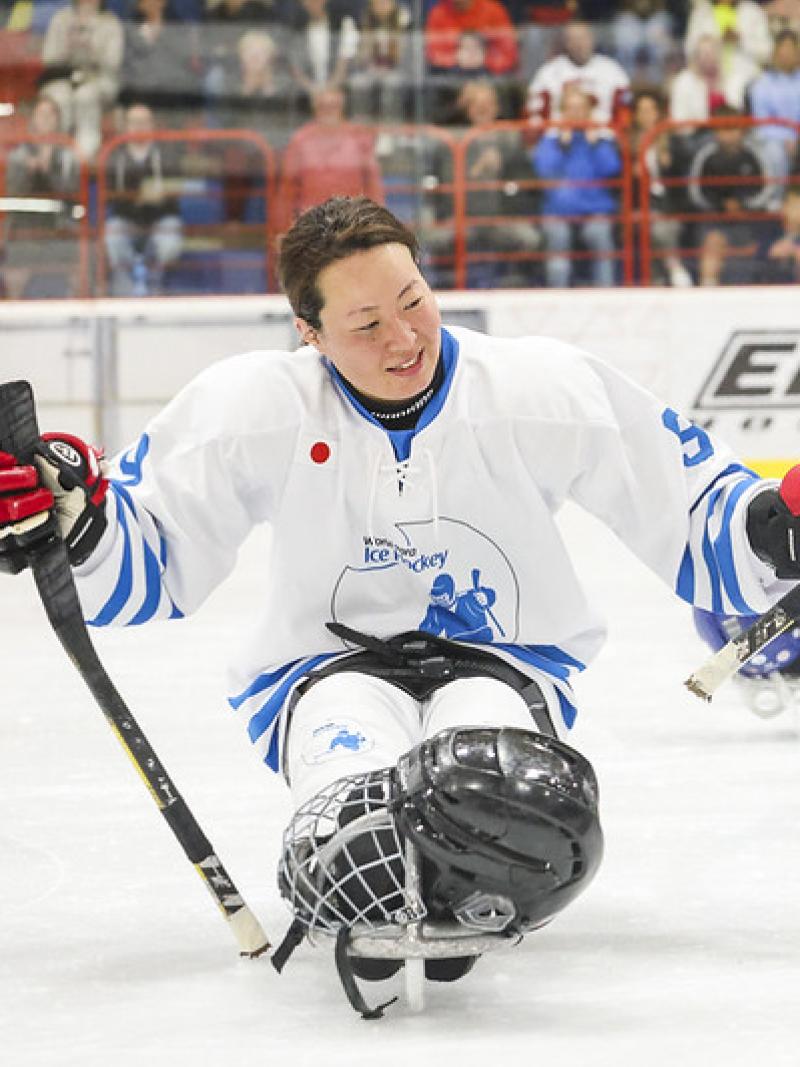 A female Para ice hockey player parading in front of her teammates