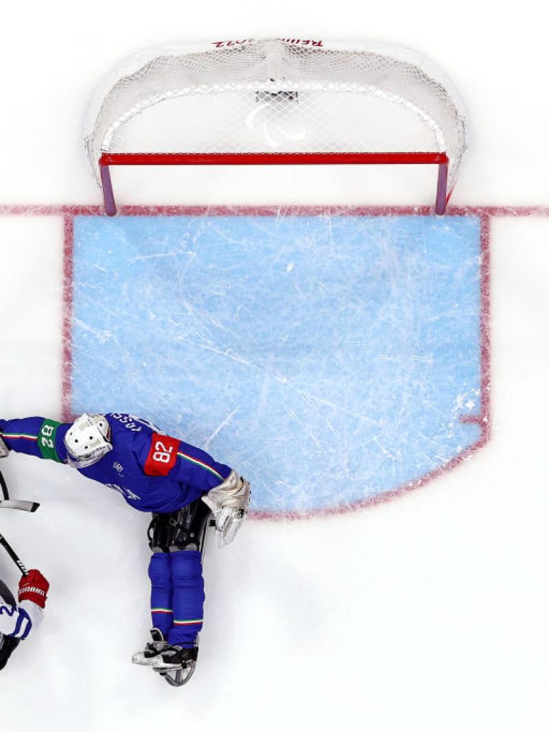 An aerial view of a Para ice hockey player scoring in front of a goaltender
