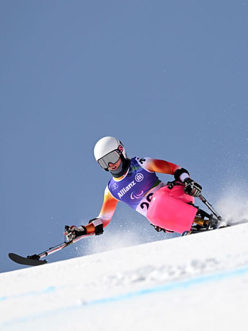 A woman in a pink sit-ski takes a downhill bend