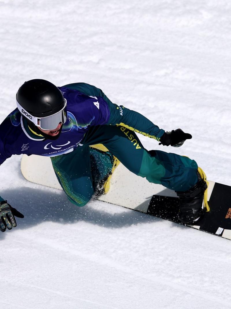 A male Para snowboarder doing a turn on the snow park