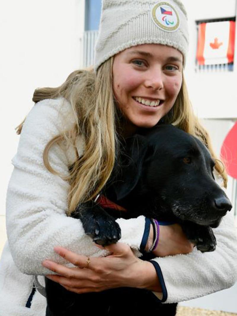 A female Para athlete hugs a black dog