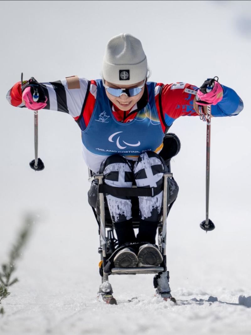 Two female sit-skiers race side by side