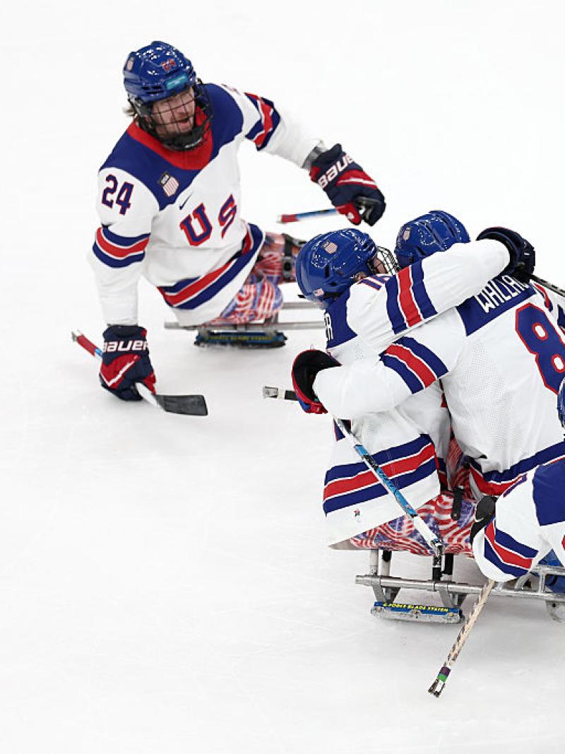 Five USA Para ice hockey players hug and celebrate on ice