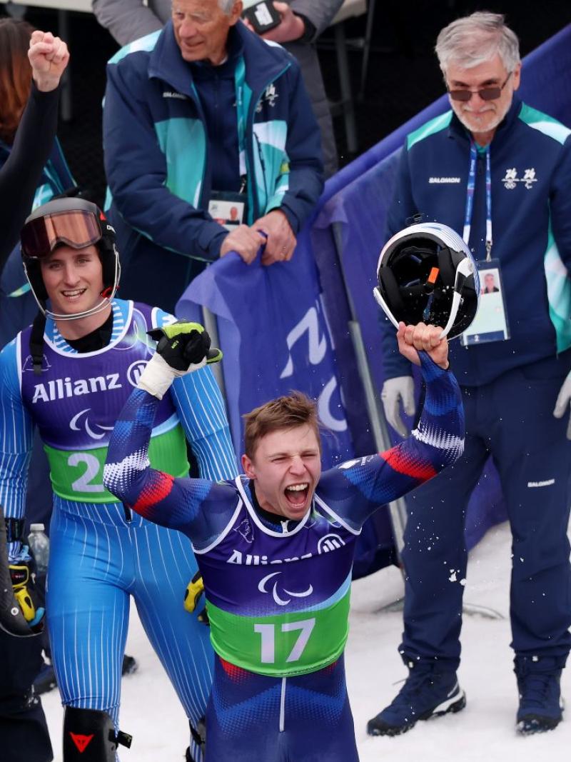 A male athlete is celebrating in front of athletes and volunteers