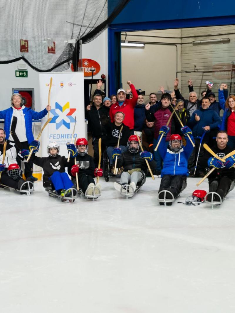 A group of people on sledges and standing on an ice hockey rink