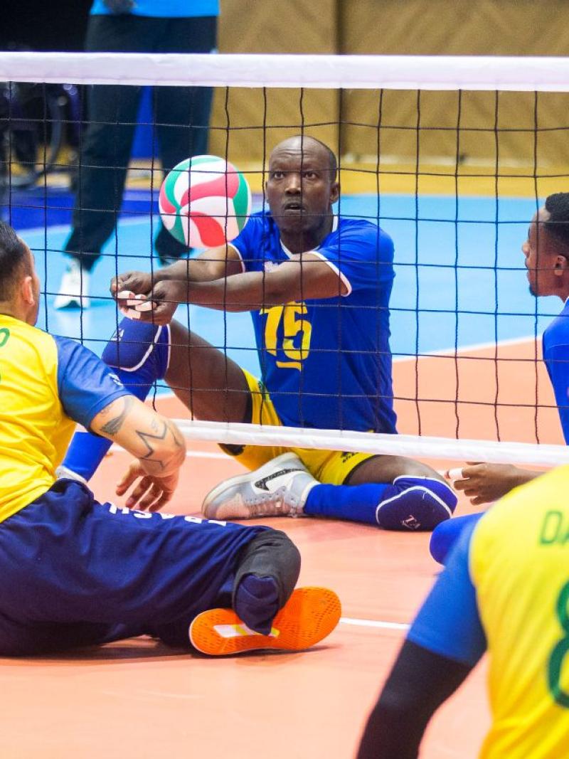 A male sitting volleyball athlete is in action, returning the ball