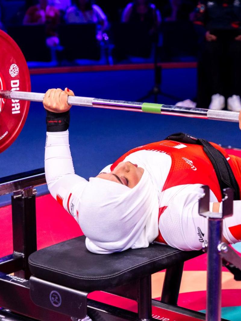 A female Para powerlifter preparing to lift the bar in a competition