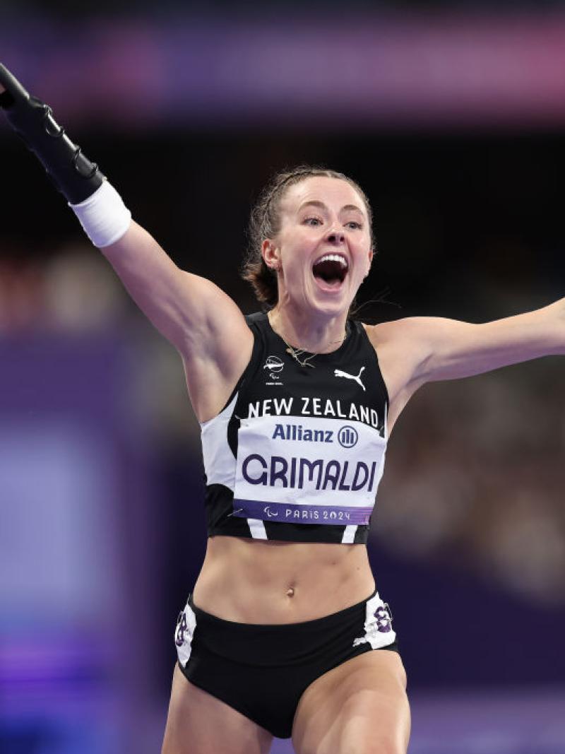 A female athlete with a prosthetic arm celebrating in a race