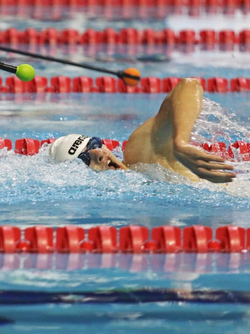 A male swimmer with blackened goggles in a race