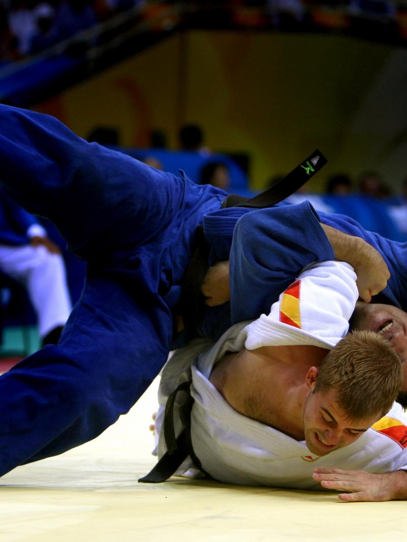 Two judo athletes fighting on the ground.