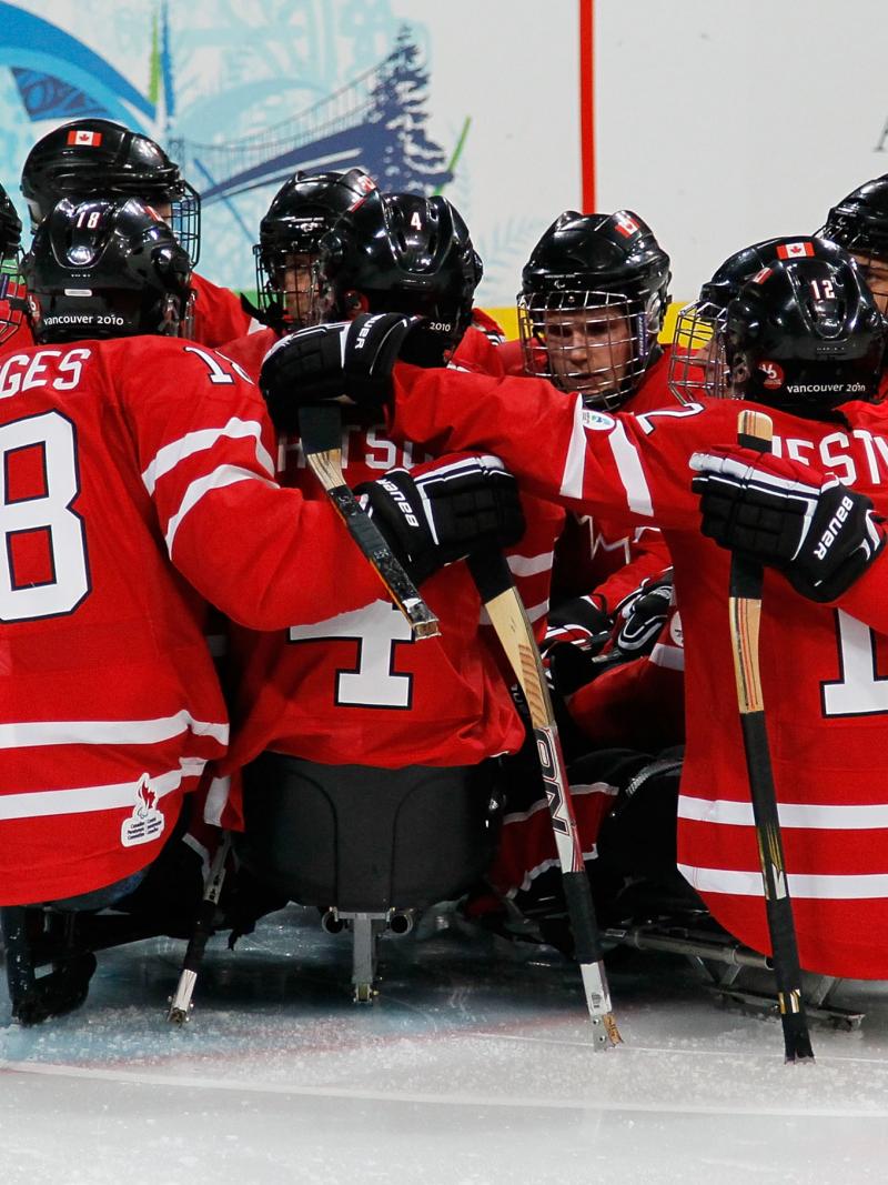 The Canadian Ice Sledge Hockey Team gathered around the goal.