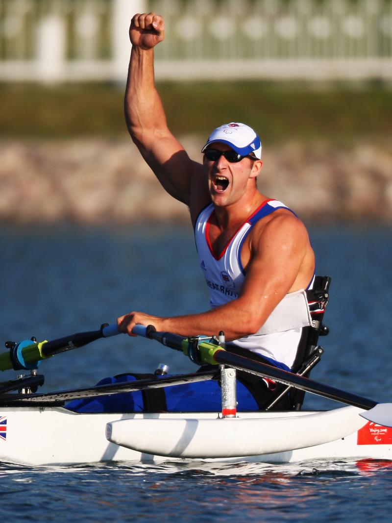 British male rower holds fist in air in celebration