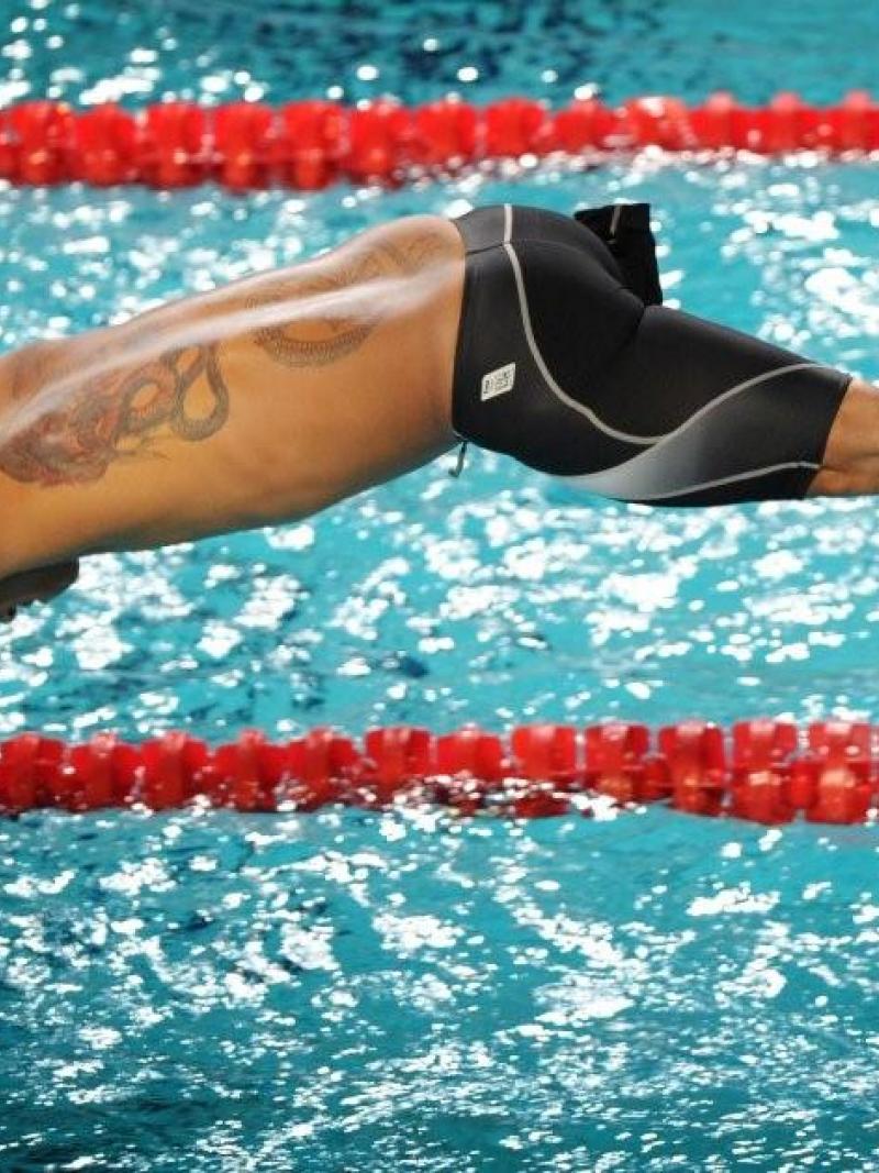 Swimmer starts a race from the start block jumping in the water.