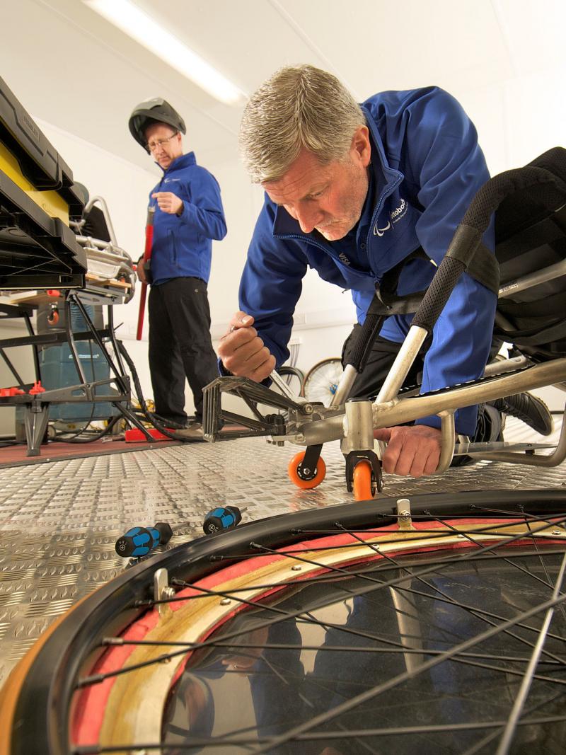 A picture of man fixing up a wheelchair