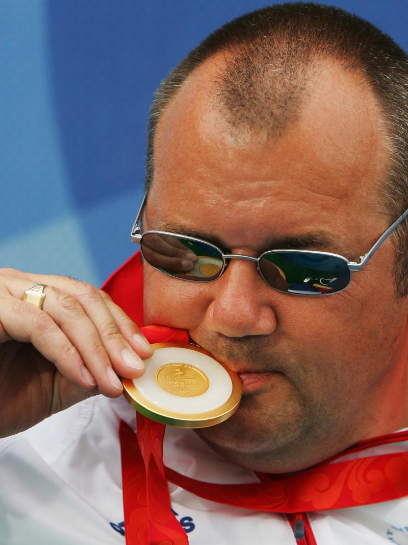 A picture of a man kissing his gold medal