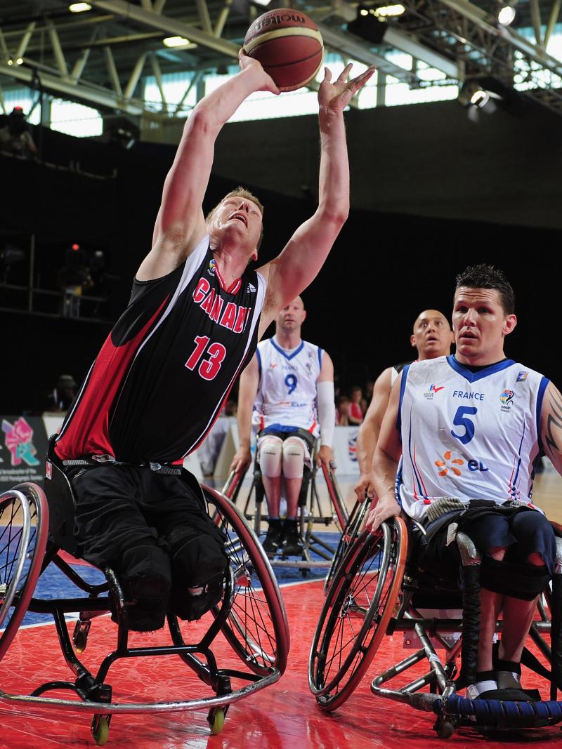 A picture of a man in a wheelchair shooting a ball in a Wheelchair Basketball match
