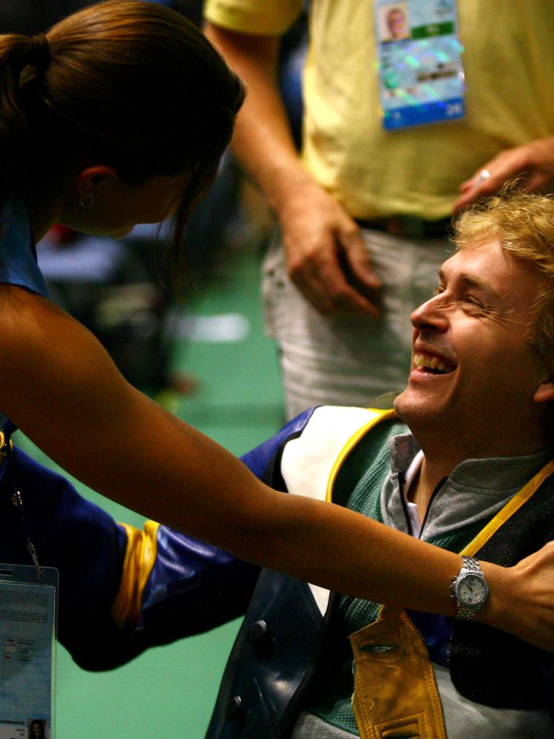 A picture of a man in a wheelchair congratulated by a woman