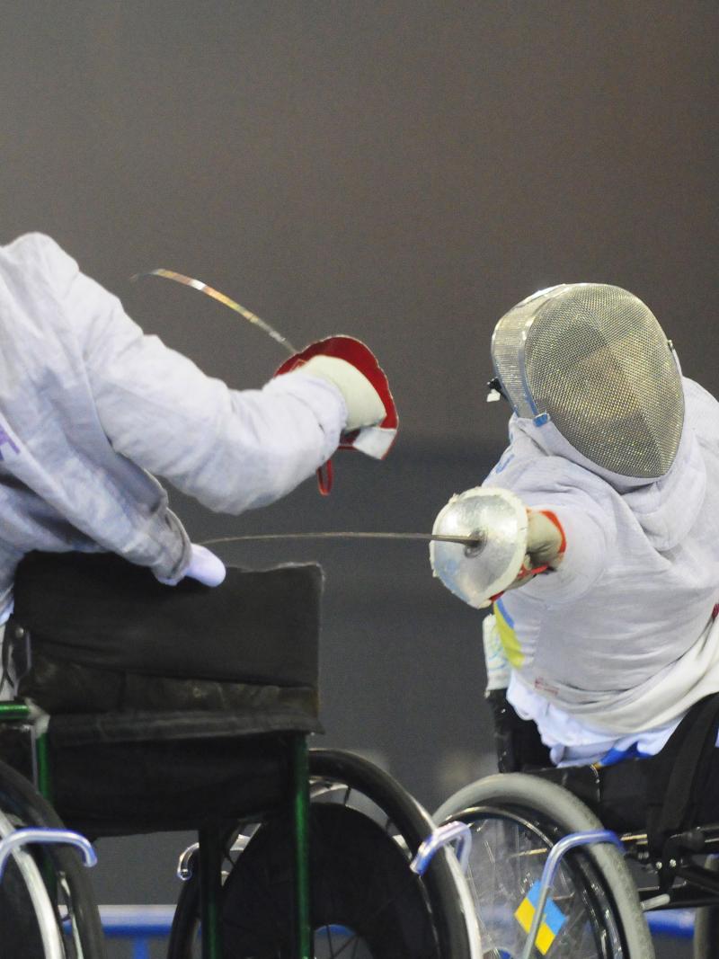 A picture of 2 mens in wheelchair practising fencing