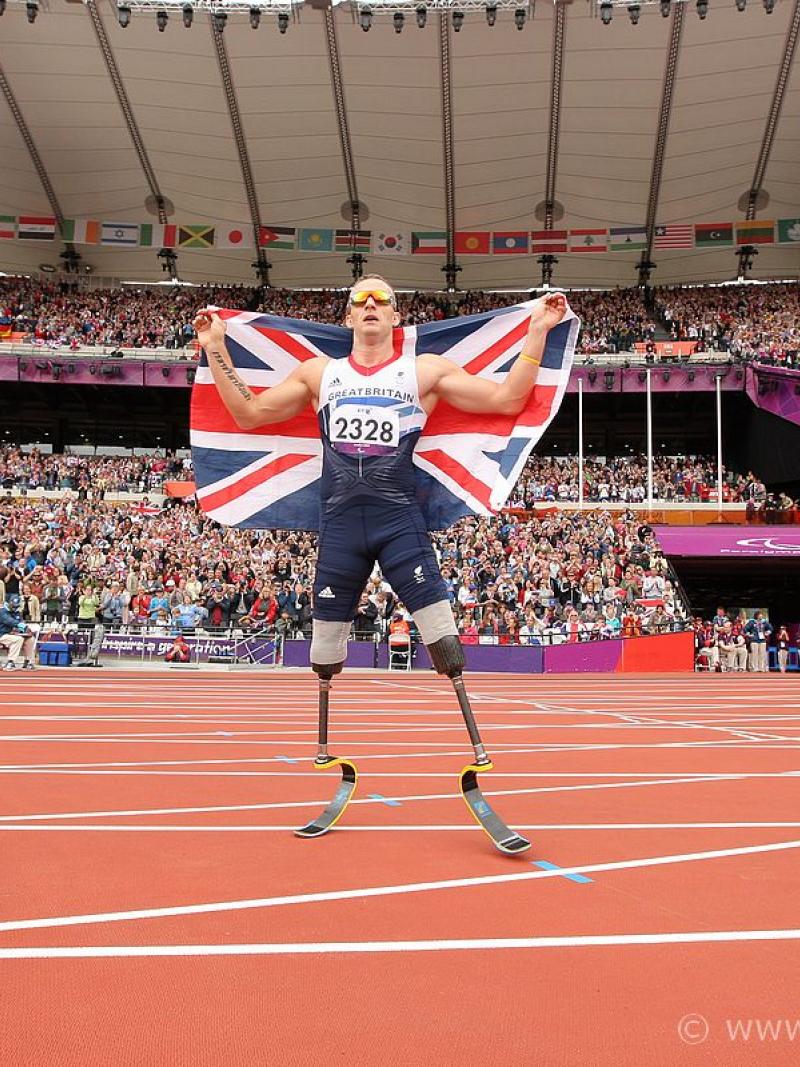 A picture of a man celebrating his victory wearing a flag of Great Britain