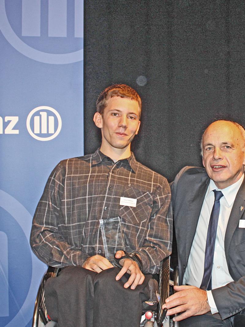 A picture of a man in a wheelchair posing with his award