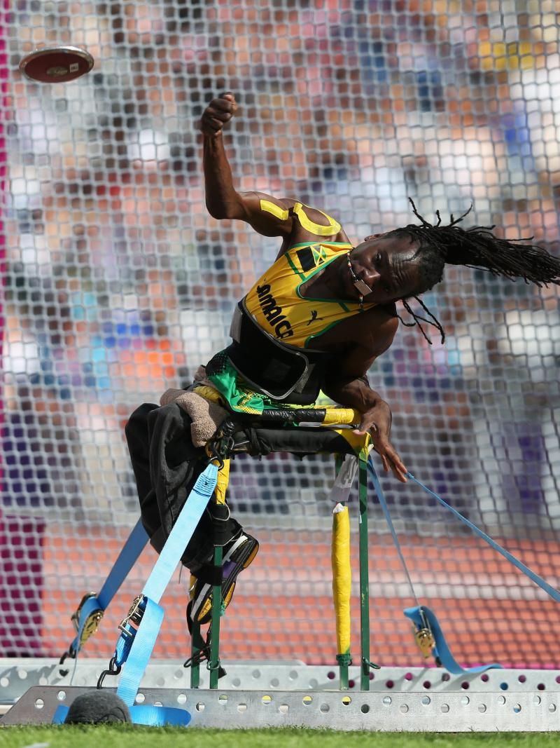 A picture of a man sit down and throwing a discus