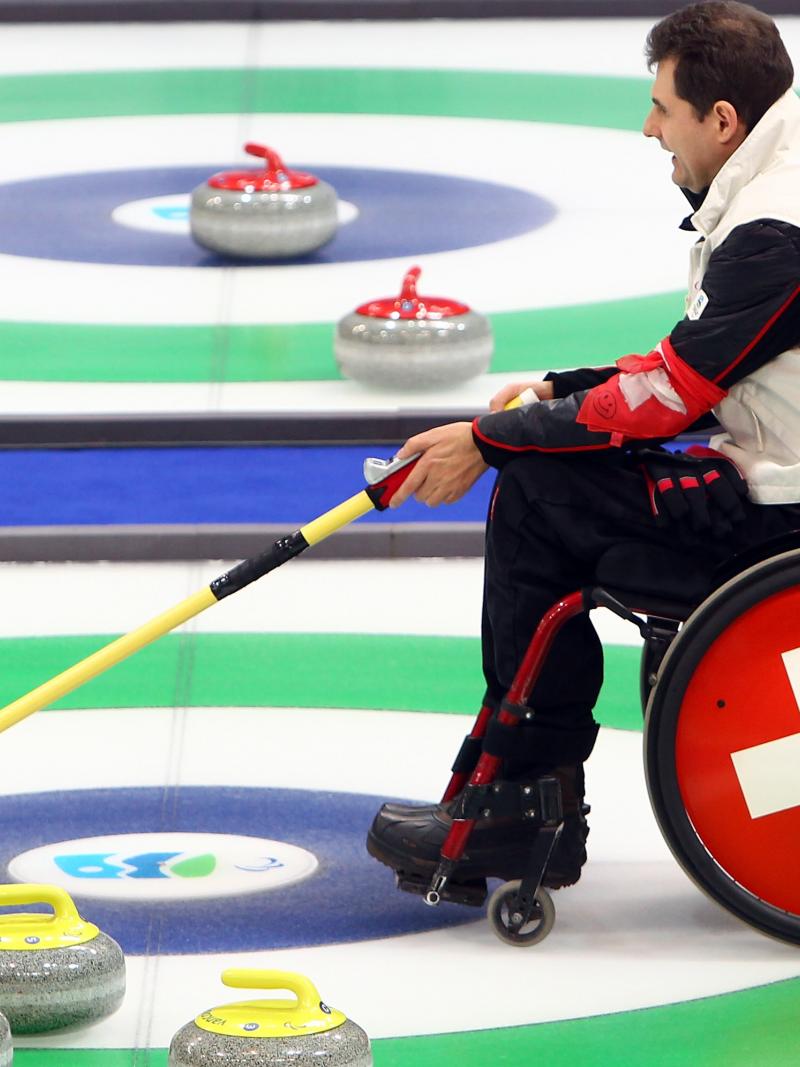 A picture of a man in a wheelchair playing Curling