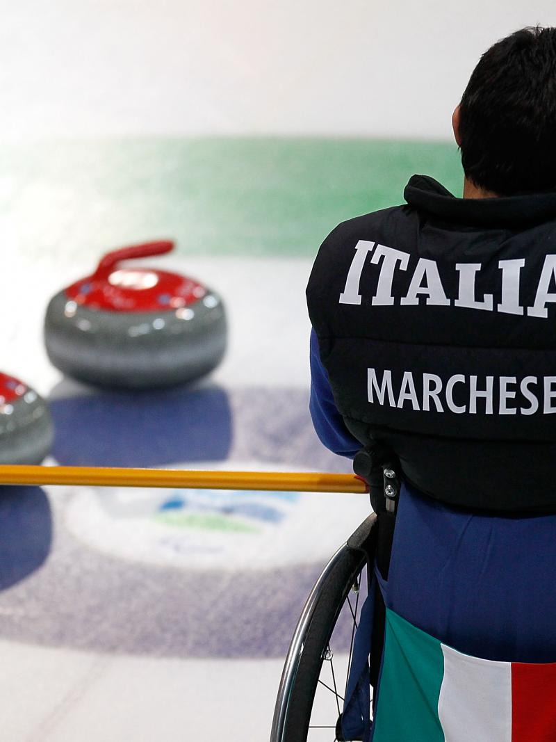 A picture of a man in a wheelchair playing curling.