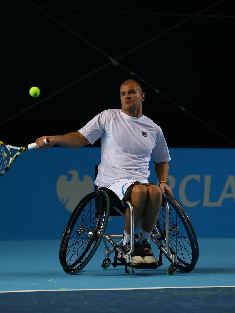 A picture of a man in a wheelchair playing tennis.