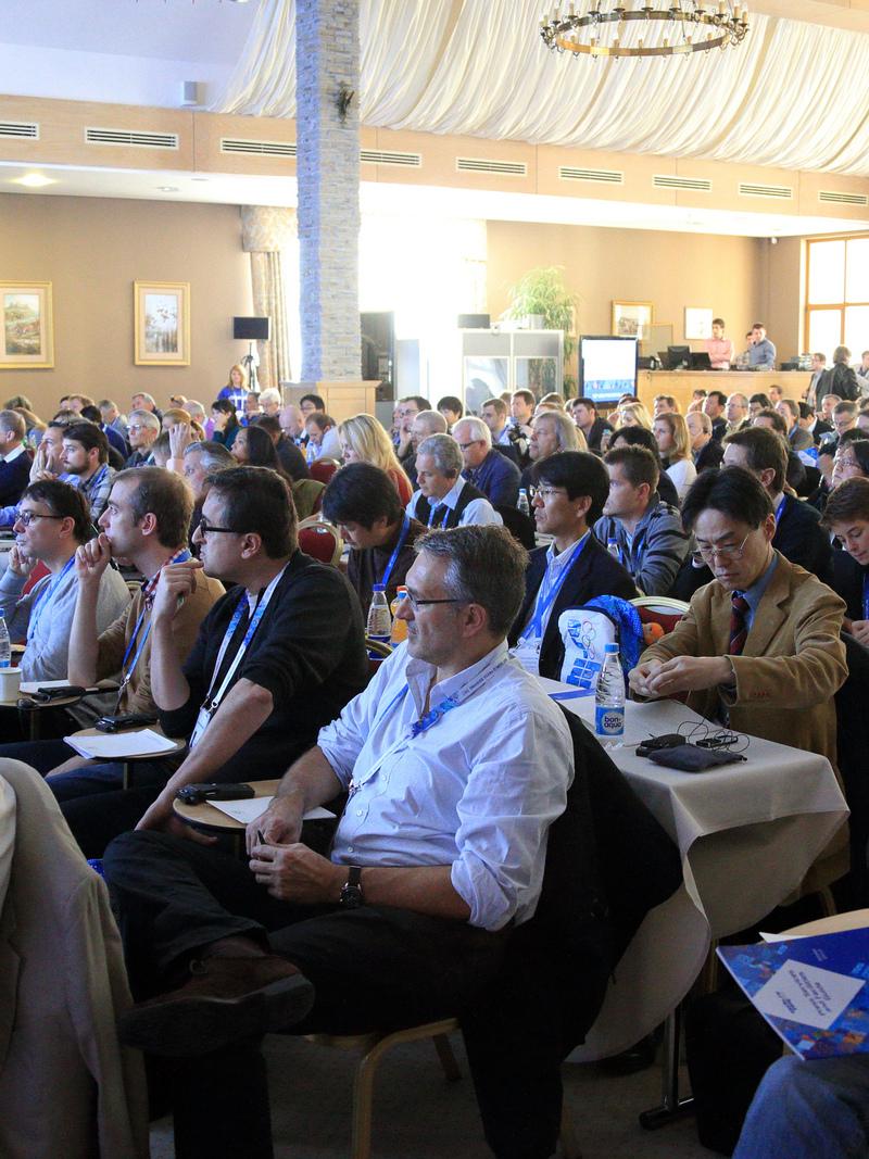 A picture of room fill in by several attendees listening a conference