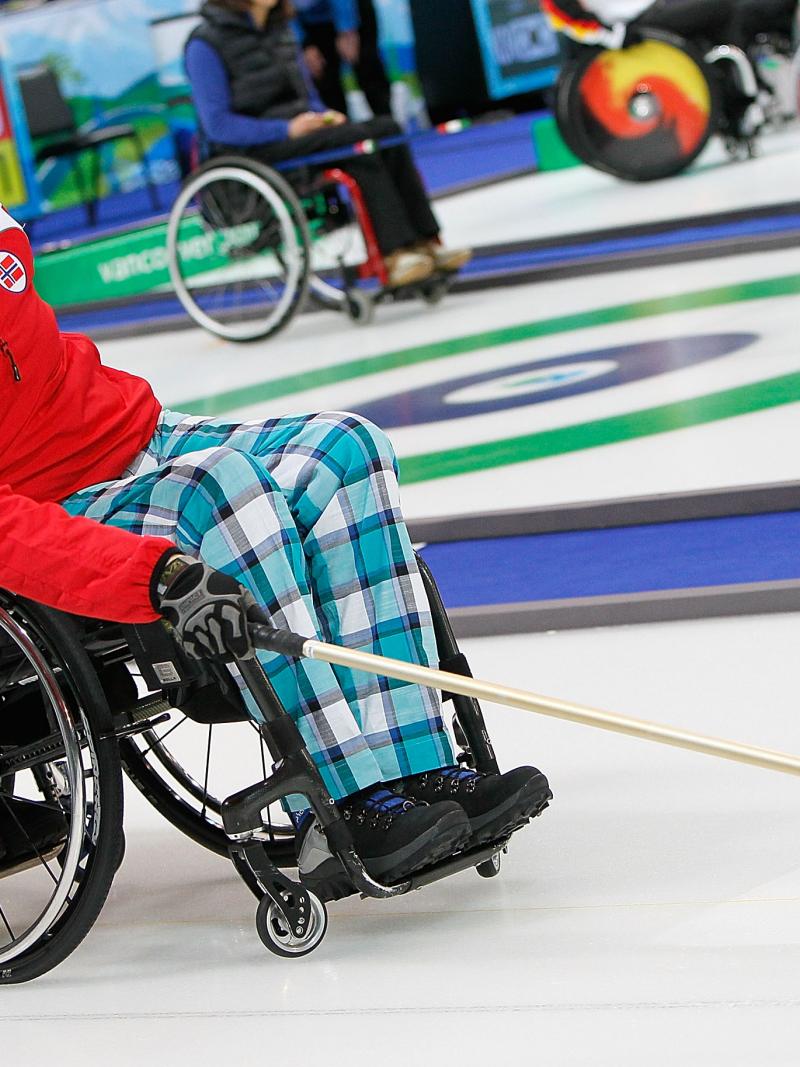 A picture of a man in a wheelchair playing curling