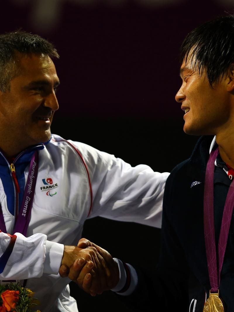 A picture of two men in a wheelchair shaking their hands