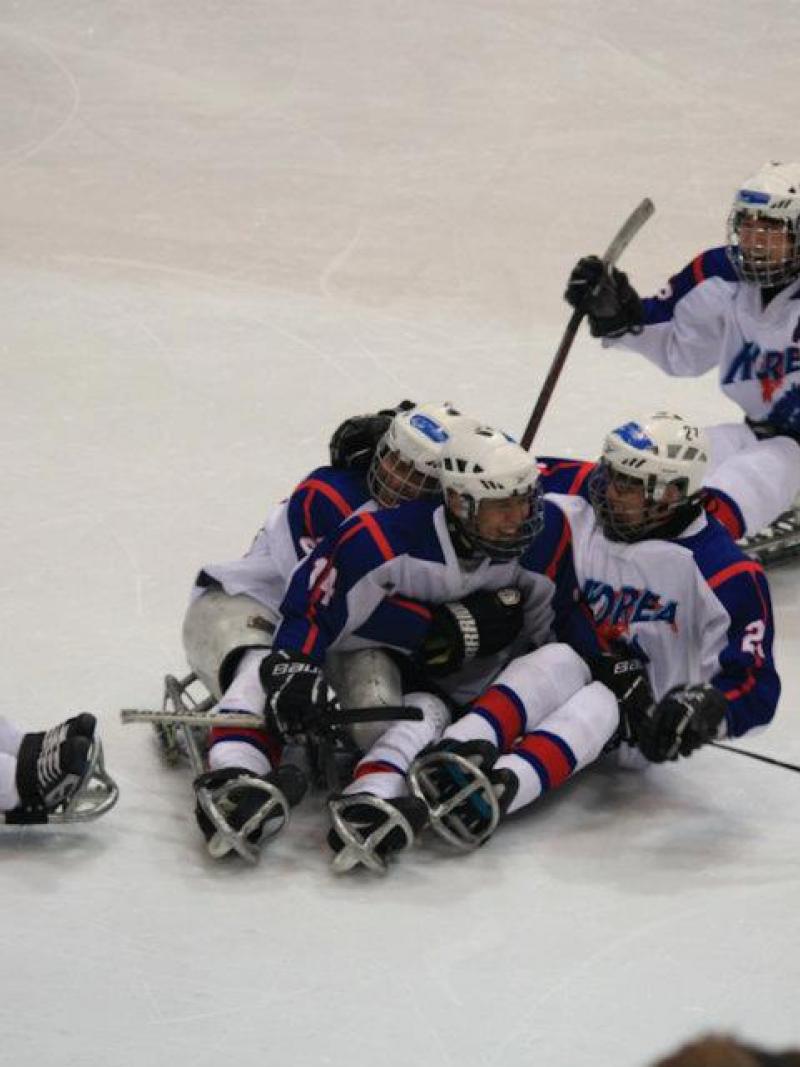 A picture of men sitting in a sledge celebrating their victory in a hockey match.