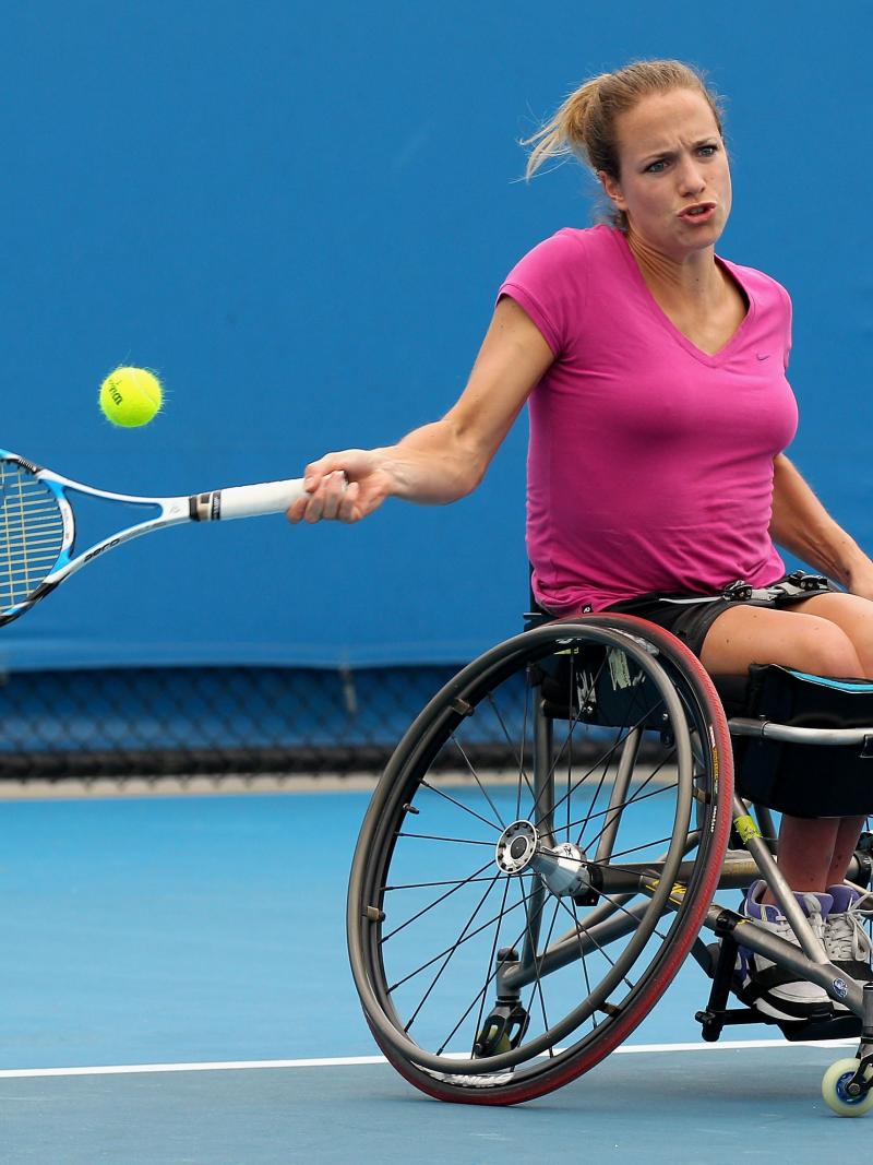Female wheelchair tennis player in action on a blue court