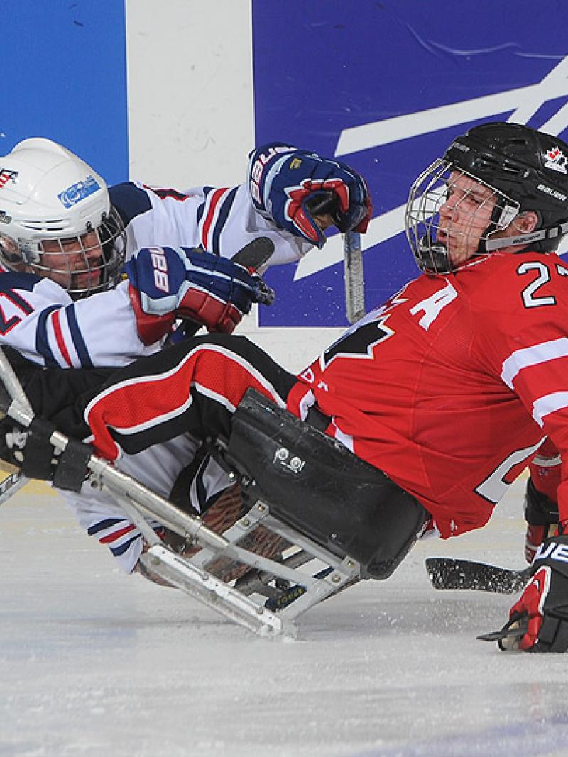 A picture of a two mens in wheelchairs playing ice hockey