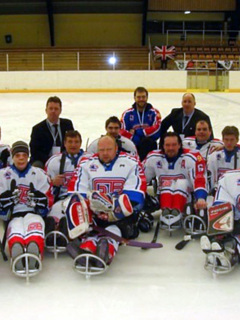 A picture of a sledge hockey team posing for a group picture