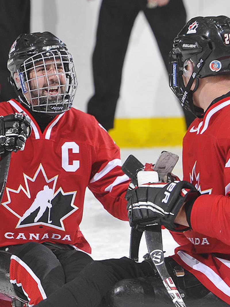 A picture of a man in sledge celebrating his victory in ice hockey match