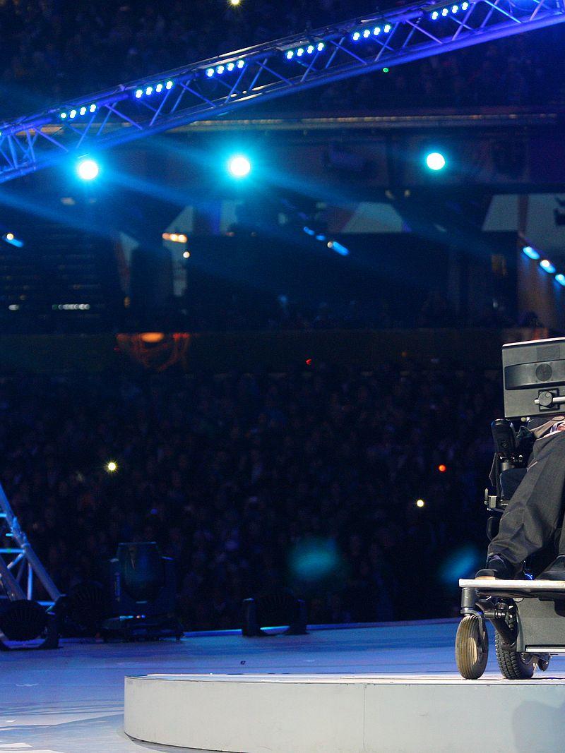 A picture of a man in an electrical wheelchair talking during a ceremony